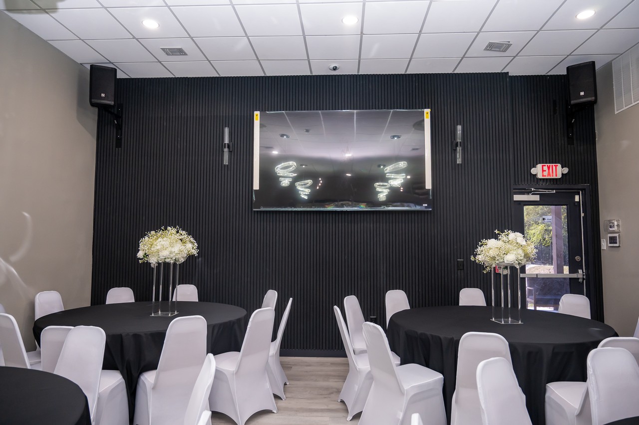 Black slatted feature wall with display screen and speakers facing decorated guest tables