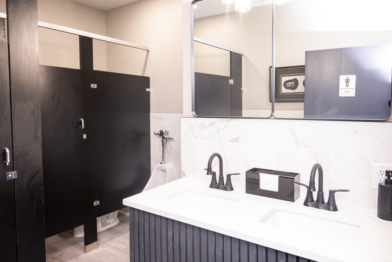 Modern restroom with dual vanity, matte black fixtures, and marble-look tile